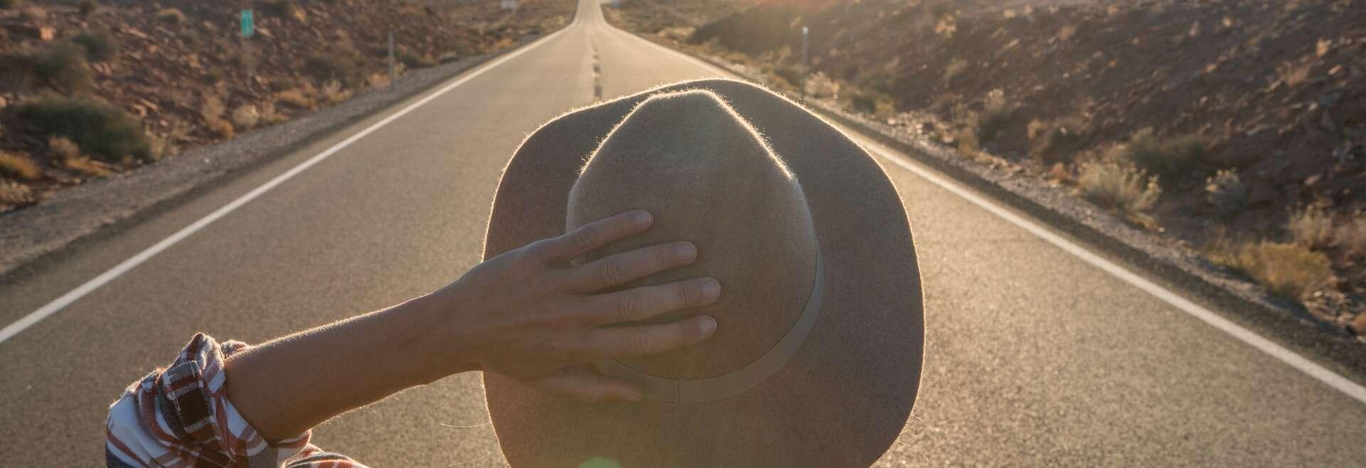 Rear view of woman standing on long highway road leading to Monument Valley in USA. People travel America concept
