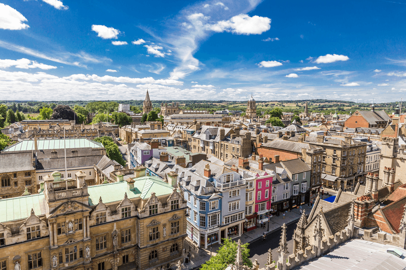 Aerial view of roofs and spires of Oxford, England with blue sky in background